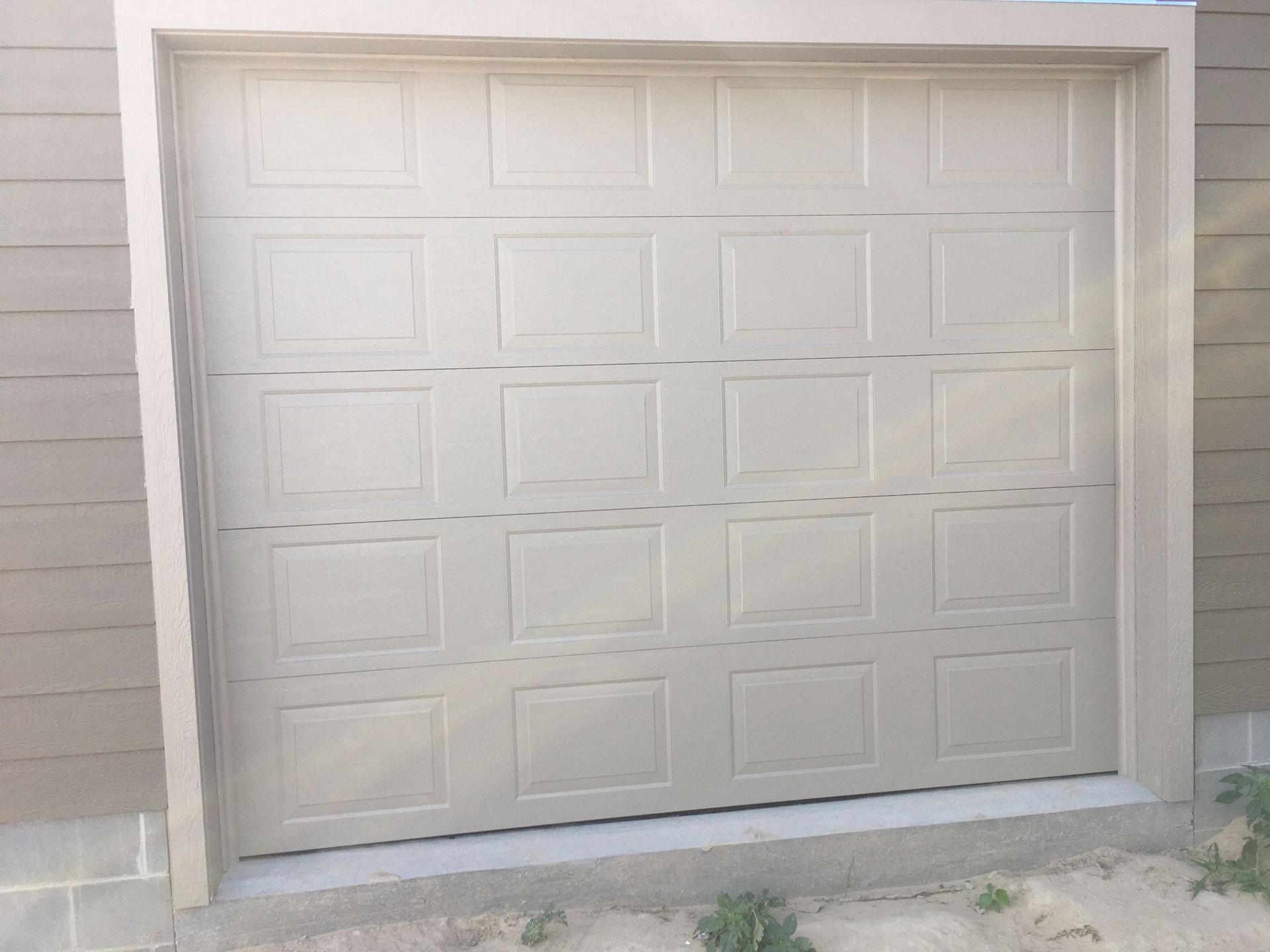 Tan closed garage door with square panel design.