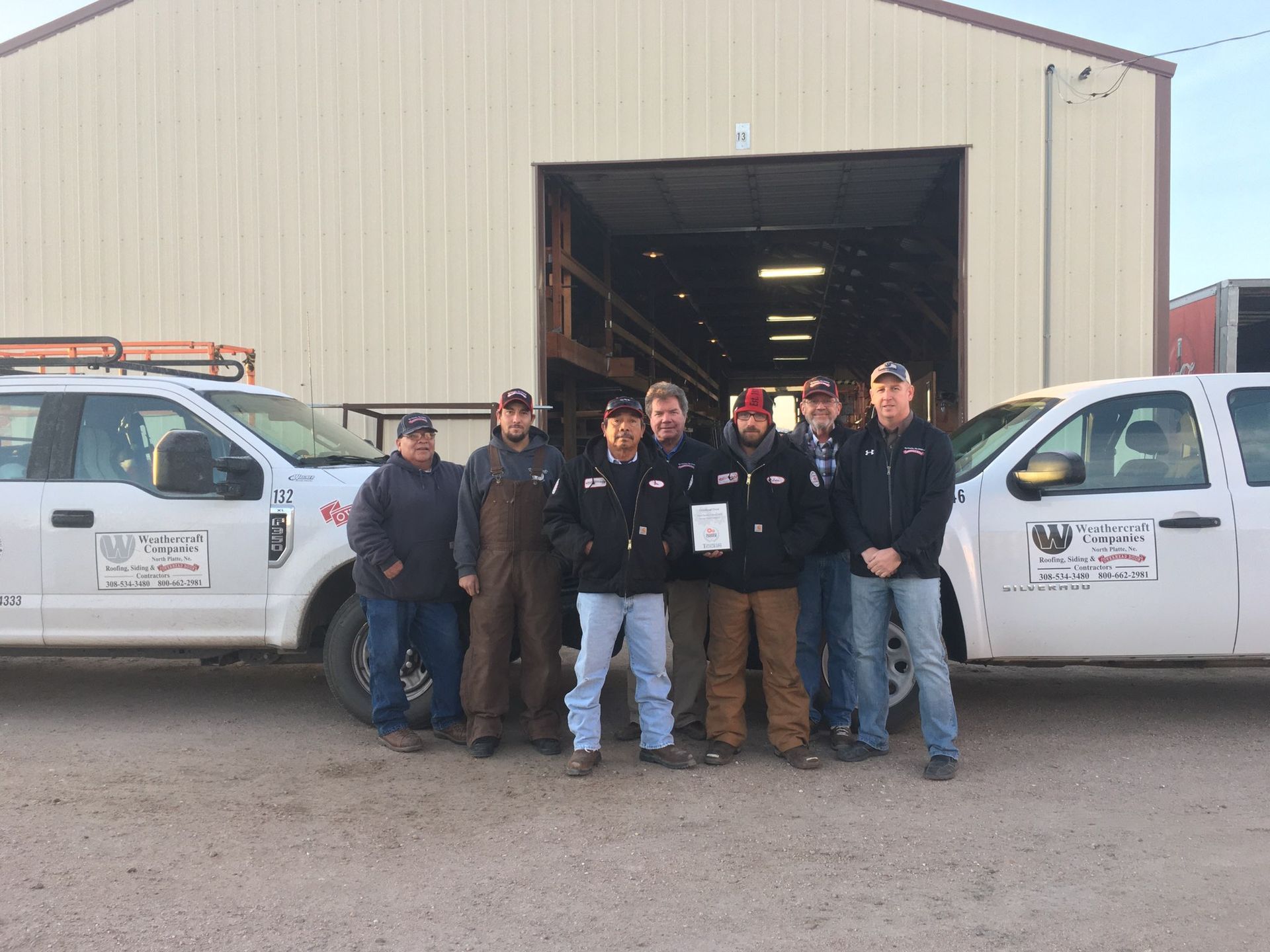 A group of men are posing for a picture in front of their trucks.