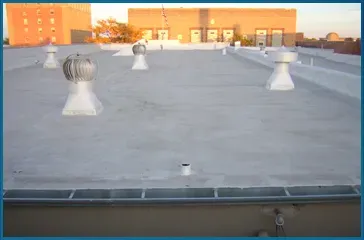 A roof with a lot of vents on it and a building in the background