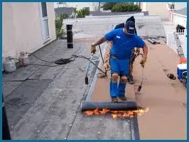 A man is working on a roof with a torch.