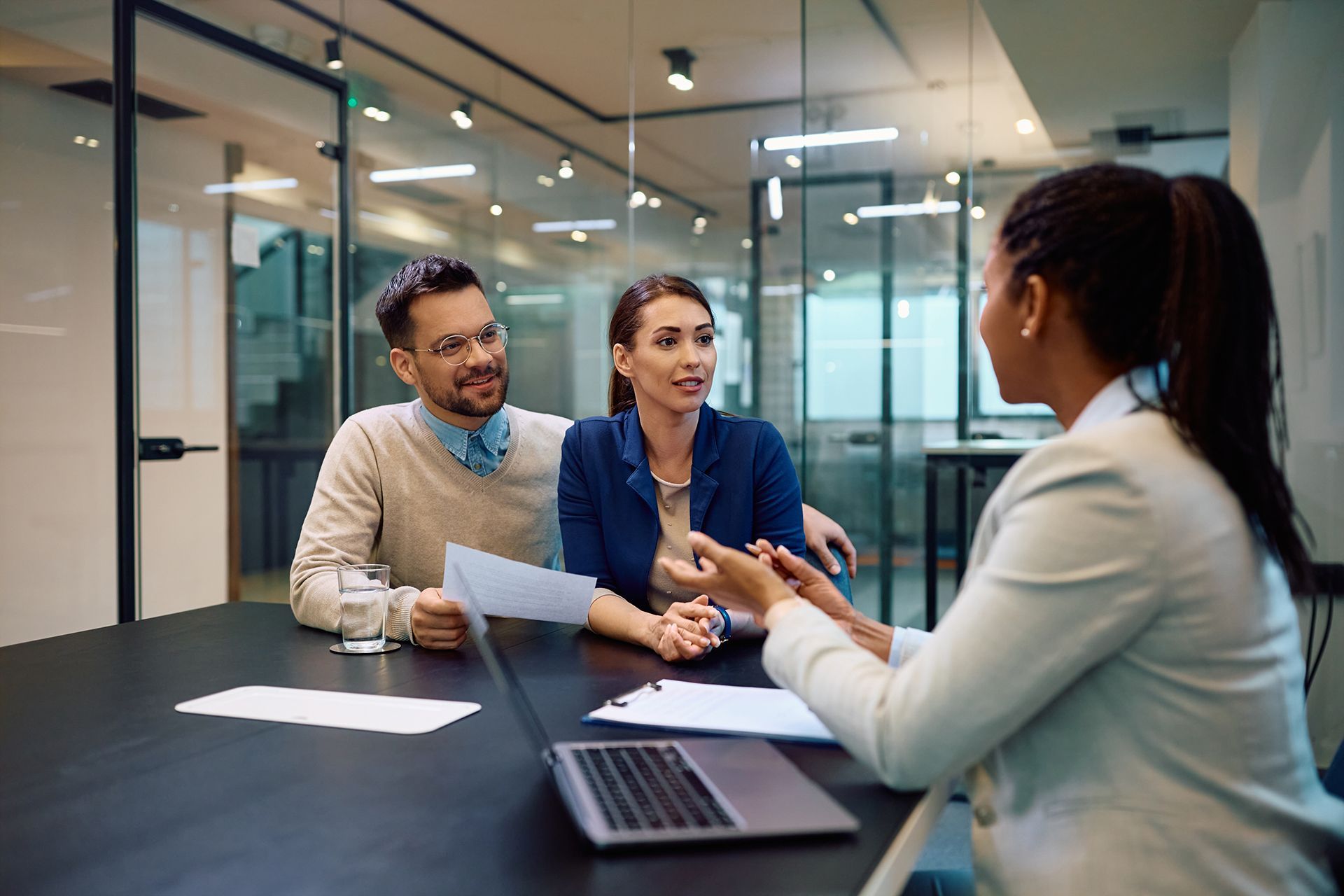 A woman is sitting at a table talking to a man and woman.