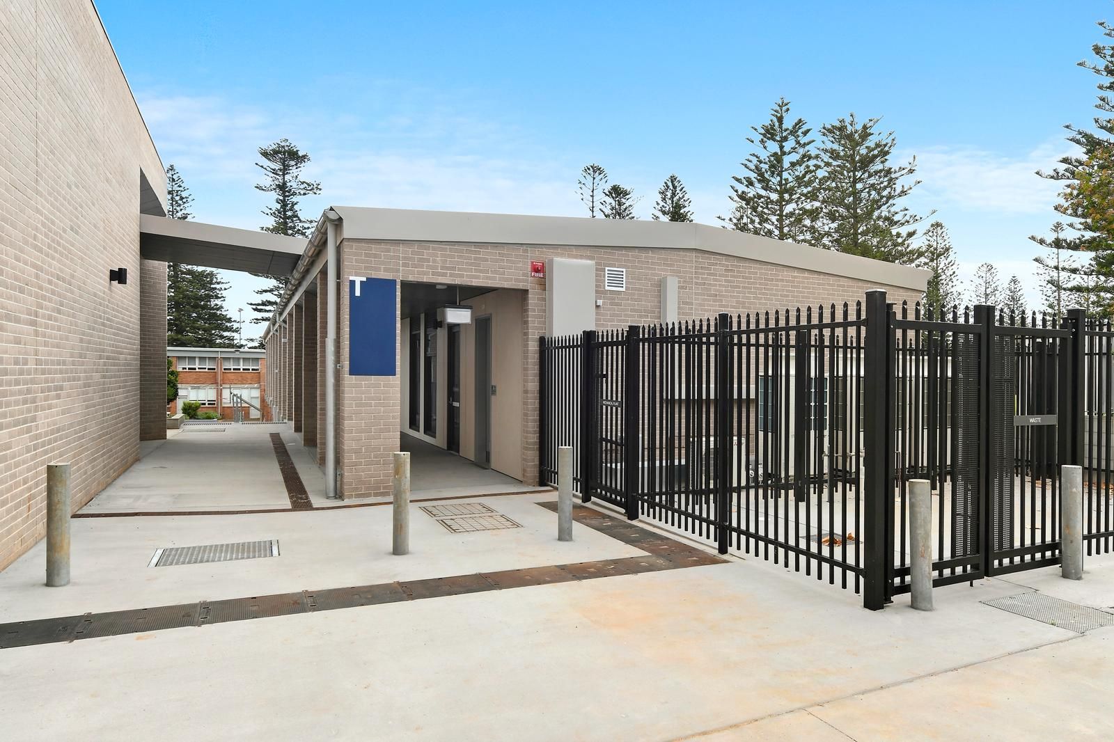 Modern building entrance with ramps, black metal fence, and concrete walkway under a clear sky — Millers Masonry In Port Macquarie, NSW