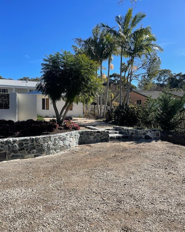 A Gravel Driveway Leading To A House With Palm Trees — Millers Masonry In Port Macquarie, NSW