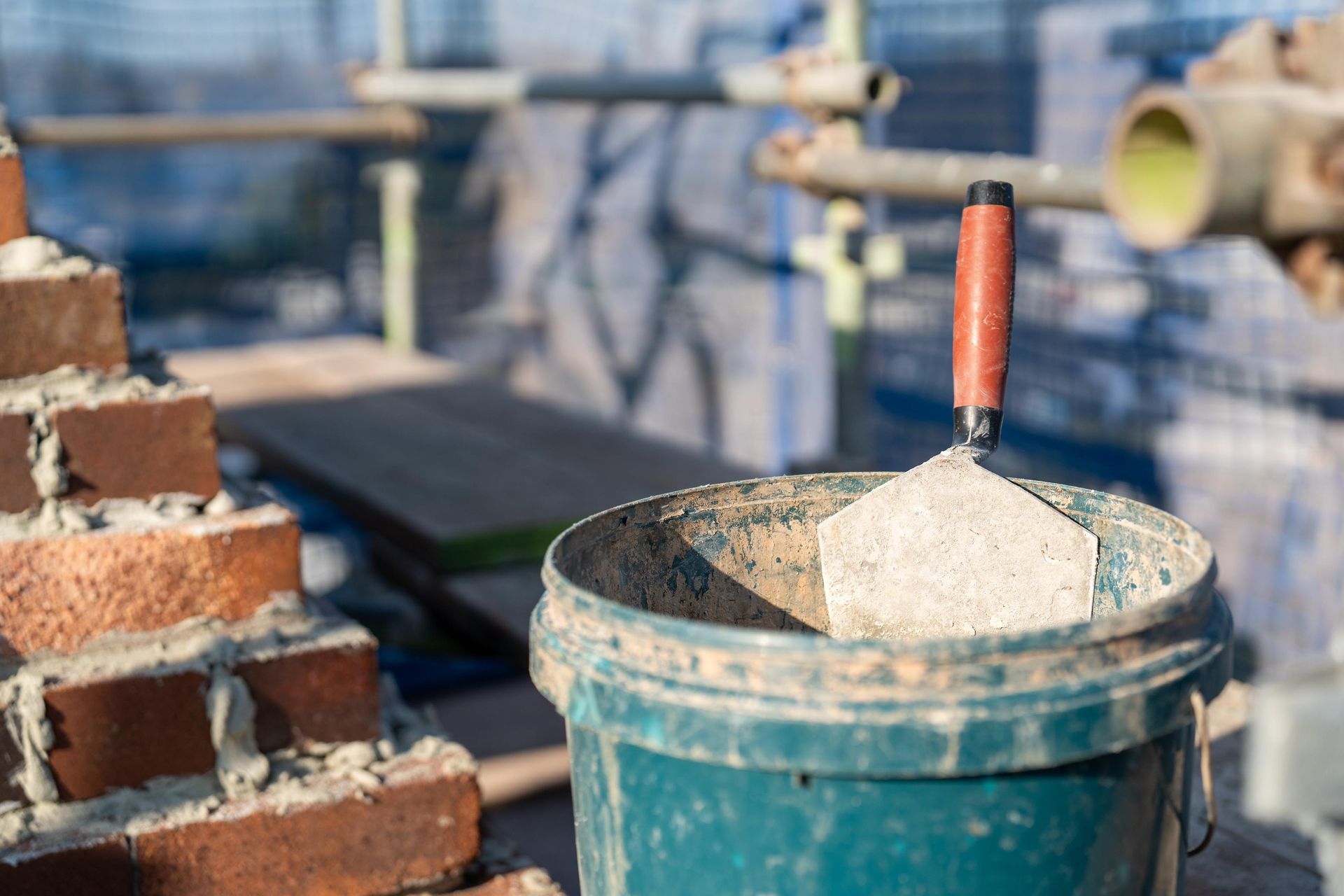 Bricklaying Scene with Trowel in Mortar Bucket Next to A Partially Built Brick — Millers Masonry In Port Macquarie, NSW