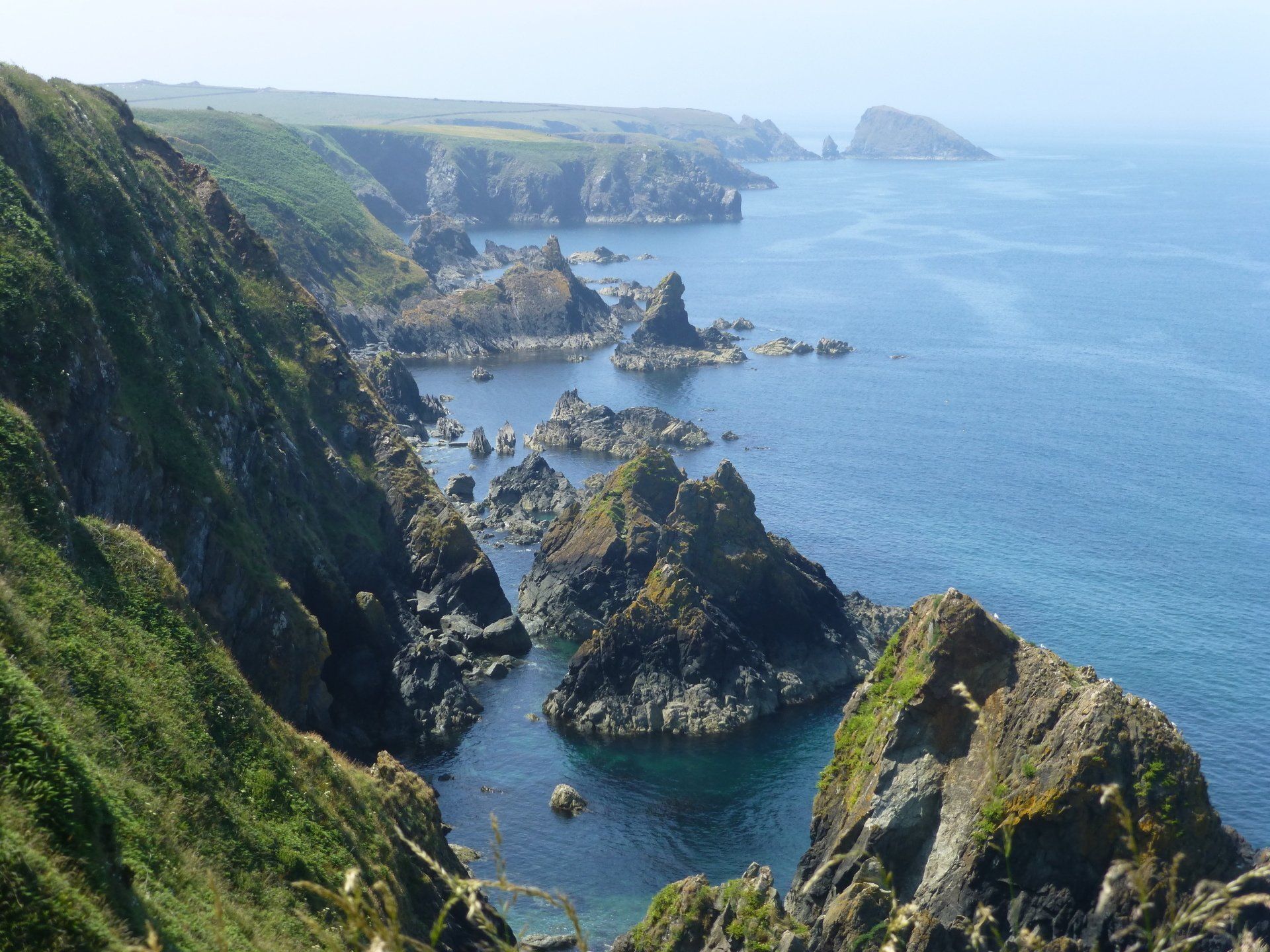 Rocky coastline with cliffs, green vegetation, and blue ocean.