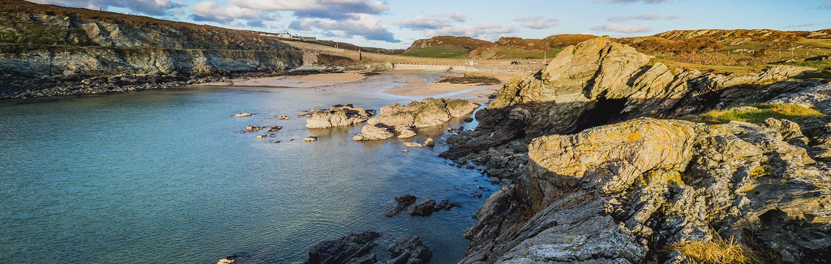 Rocky coastline and bay with turquoise water under a cloudy sky.