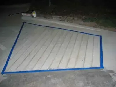 Blue taped area on concrete, with parallel lines marked inside, likely for construction or repair.