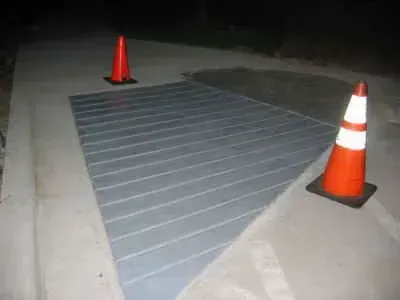 A patch of road with horizontal lines painted on it, marked by two orange traffic cones.