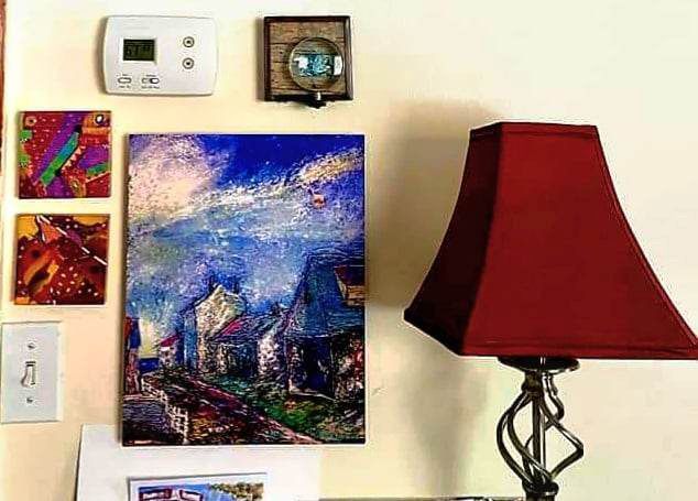 A lamp is sitting next to a painting on a wall.