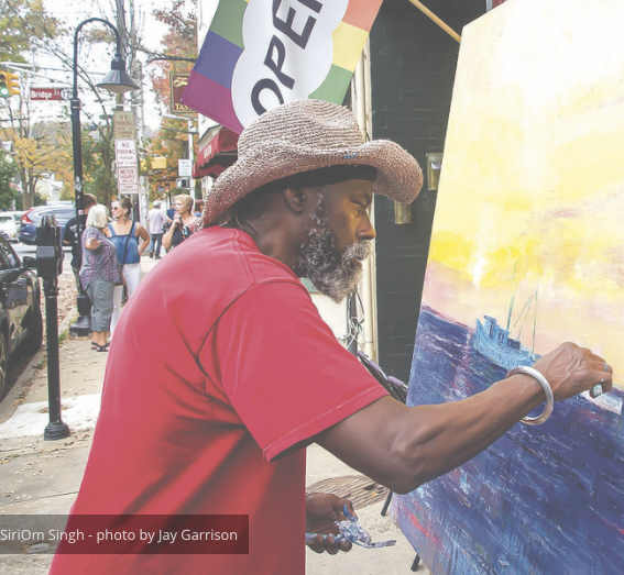 A man in a red shirt is painting on a canvas