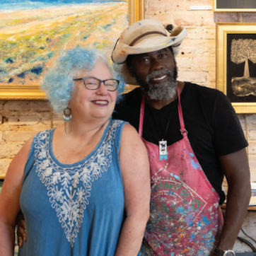 A man and a woman are posing for a picture in front of a painting