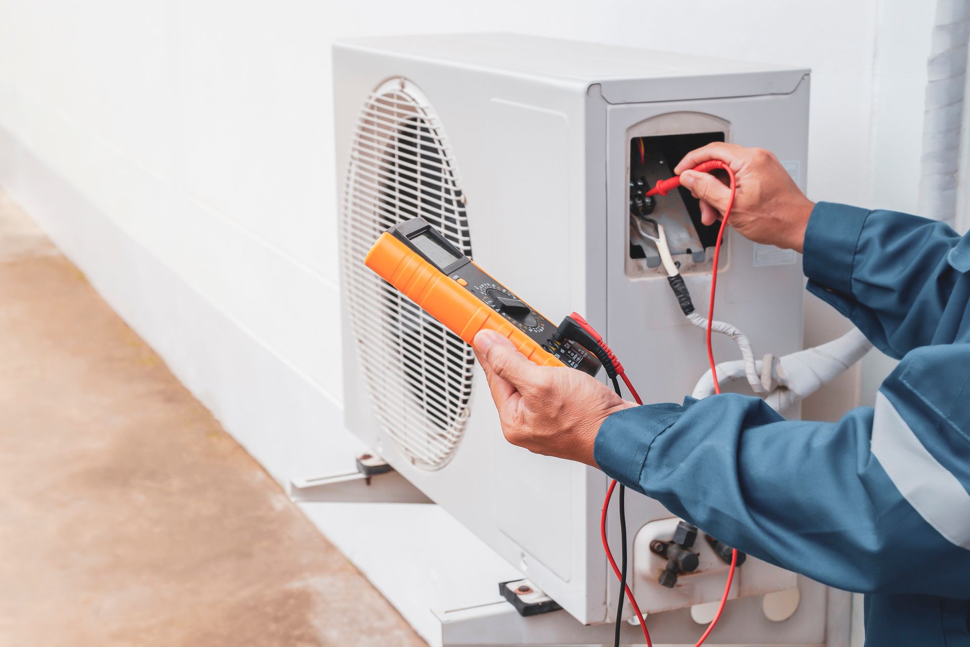 A Man Is Fixing an Air Conditioner With a Multimeter — Independence, MO — McIntosh Heating & Cooling