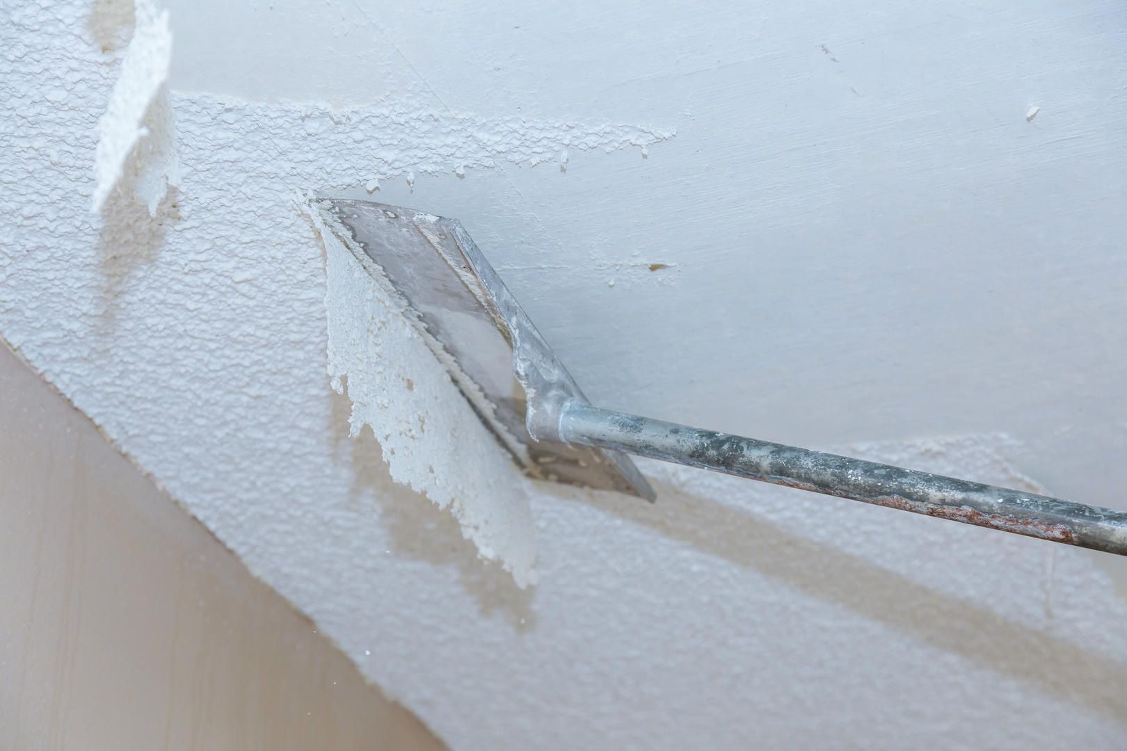 A person is plastering a wall with a trowel.