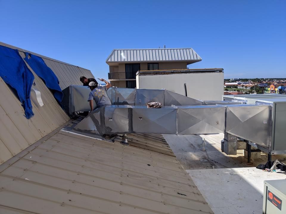 Rooftop with damaged metal panels and blue tarp over a windy, cloudy urban view