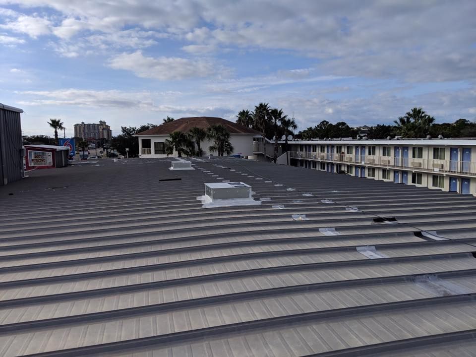 Flat rooftop with gray metal panels, low buildings, and cloudy sky in the background