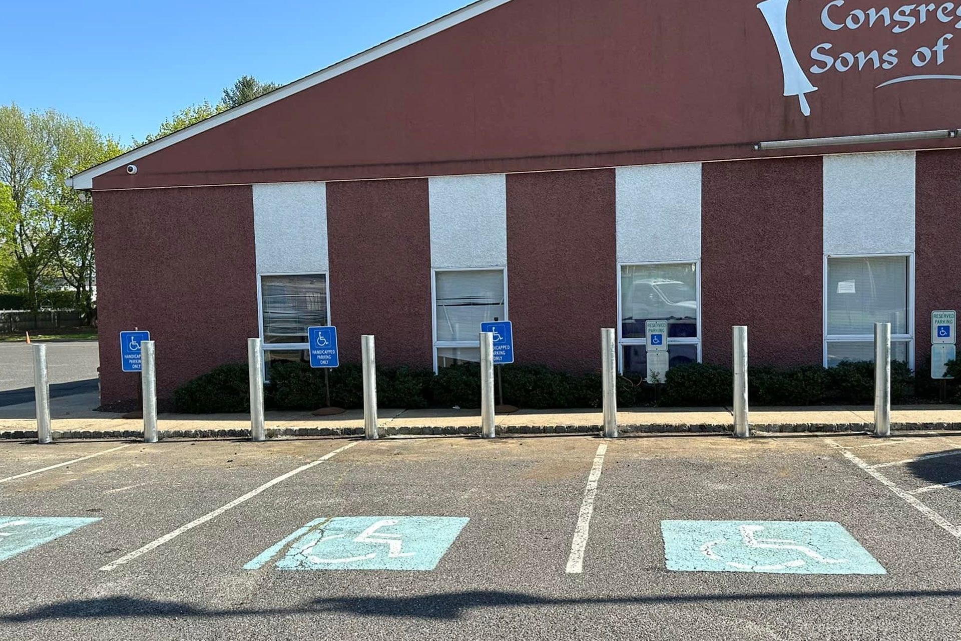 Exterior of a brick building with parking spaces and accessible parking signs.