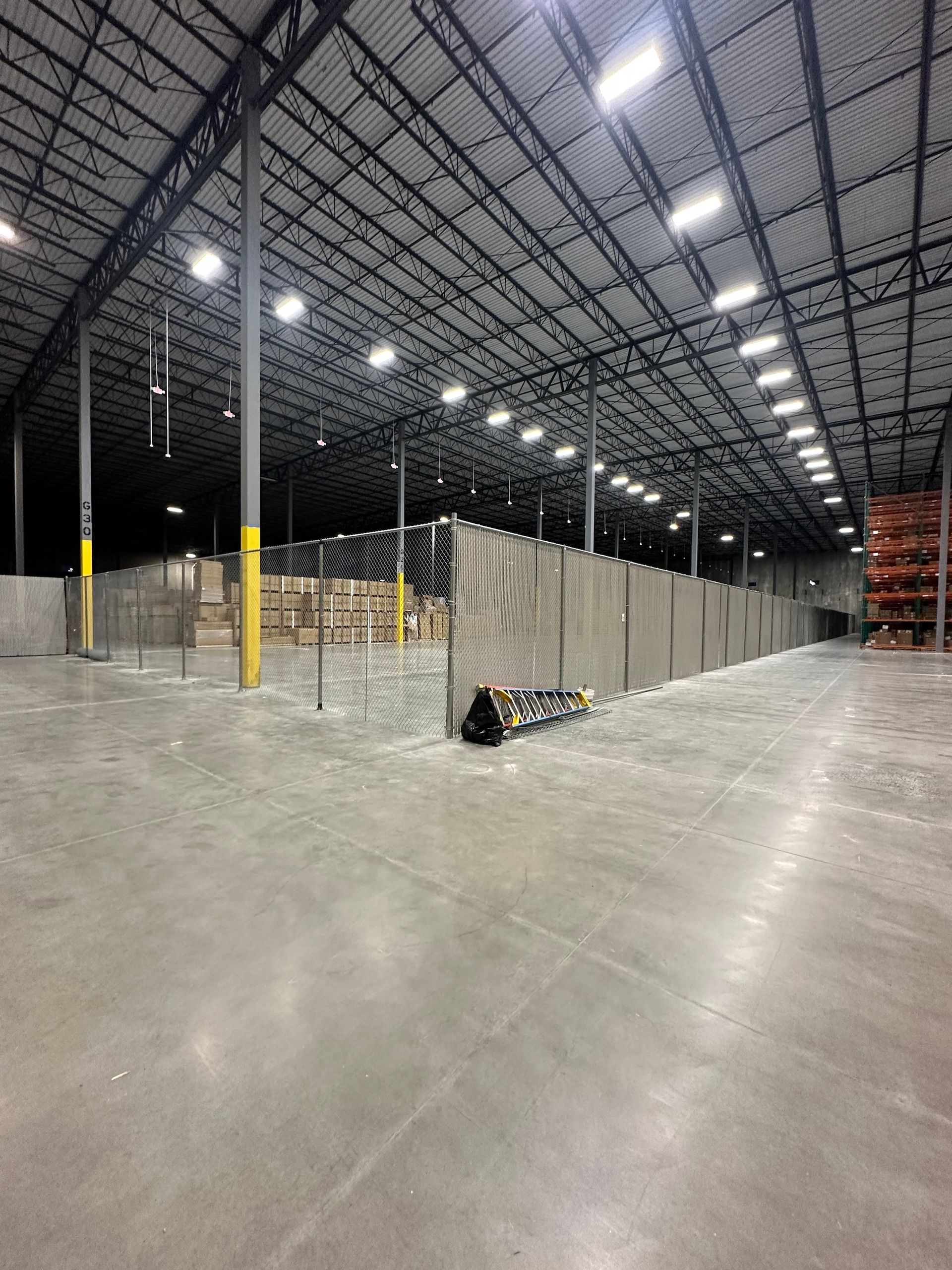 Empty warehouse interior with concrete floor, metal beams, and partition wall.