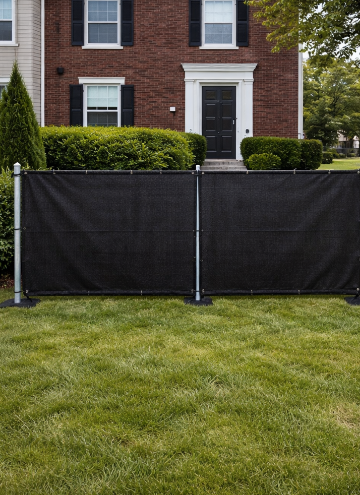 Black privacy fence in front of a brick house with a green lawn.