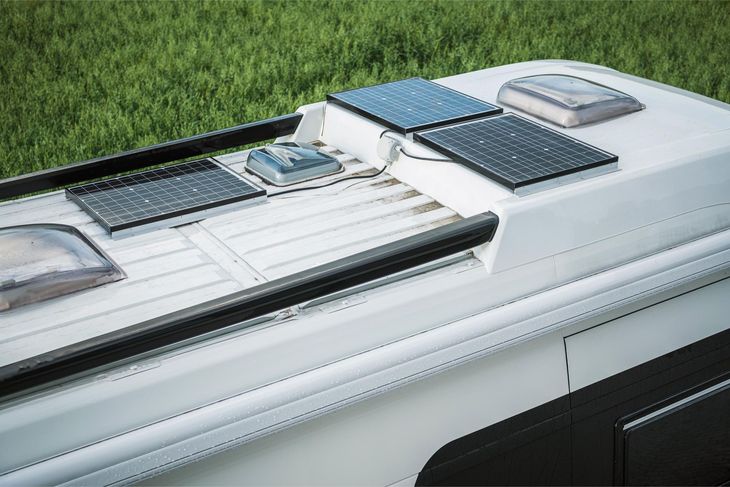 White RV roof with solar panels and vents on a grassy background