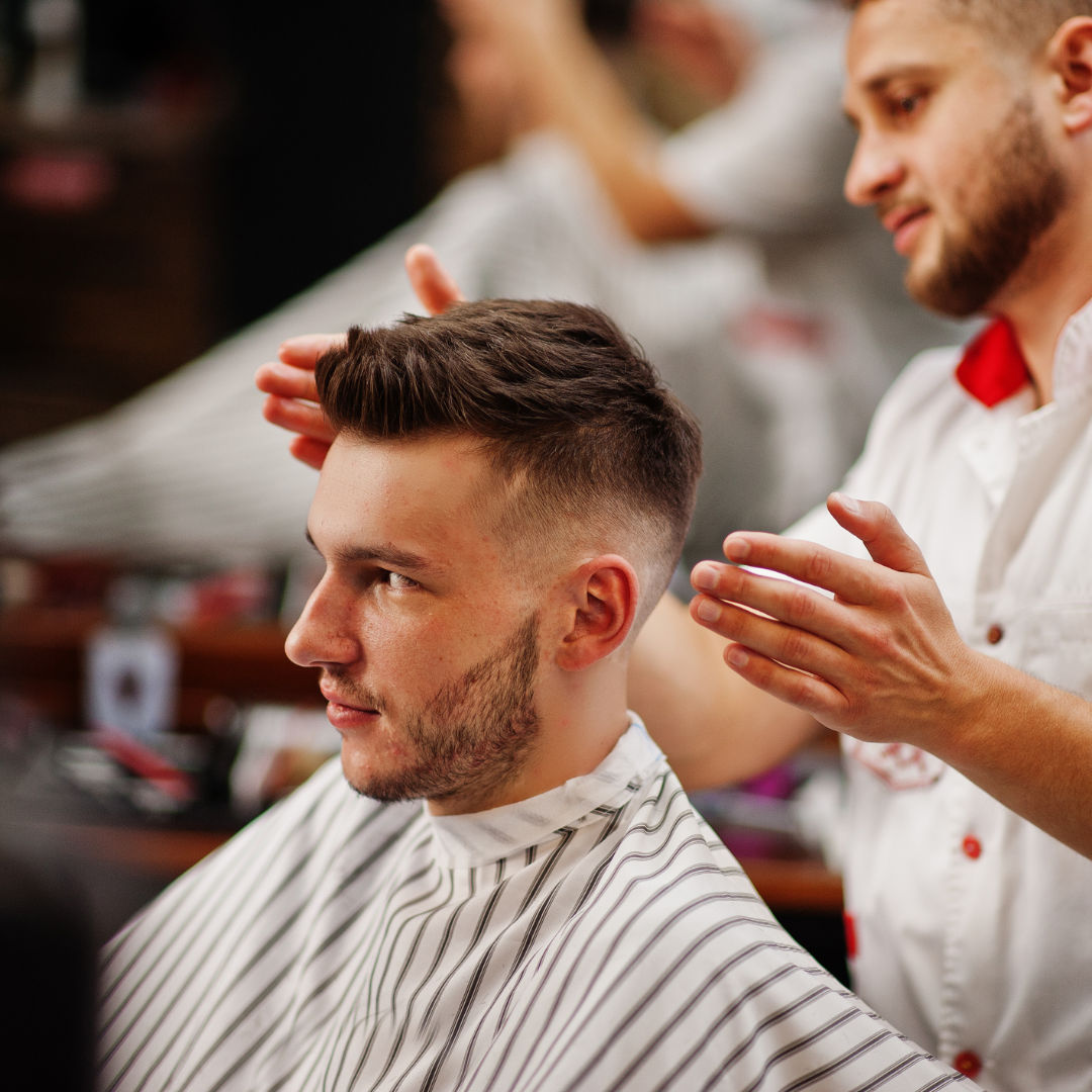 Un barbero le corta el pelo a un hombre en una barbería.