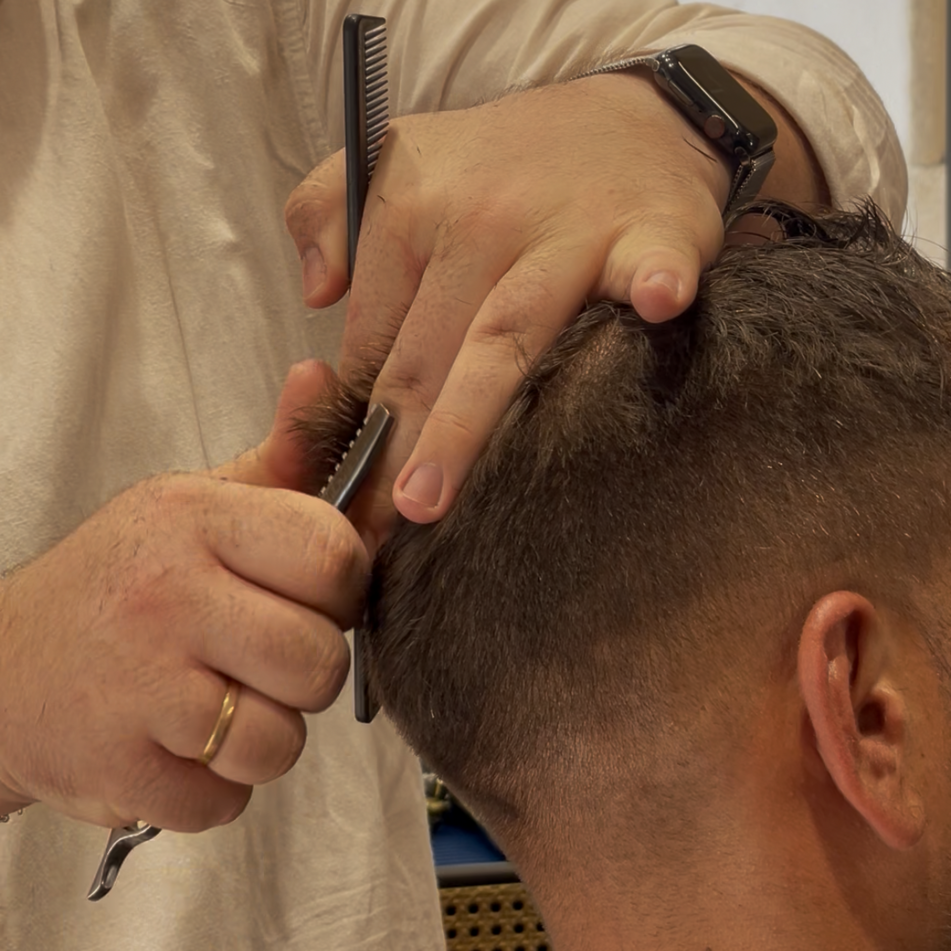 Un barbero le corta el pelo a un hombre con barba.