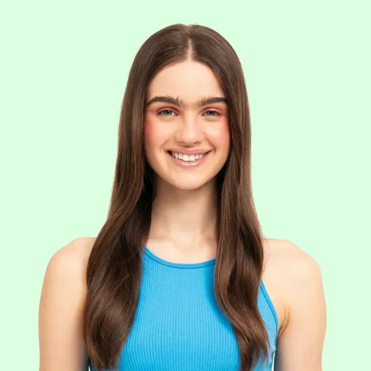 Una mujer con cabello largo lleva una camiseta sin mangas azul y sonríe.
