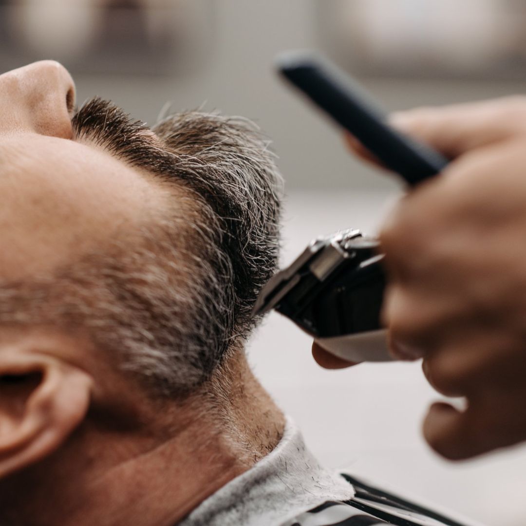 Un barbero le está cortando el pelo a un hombre.