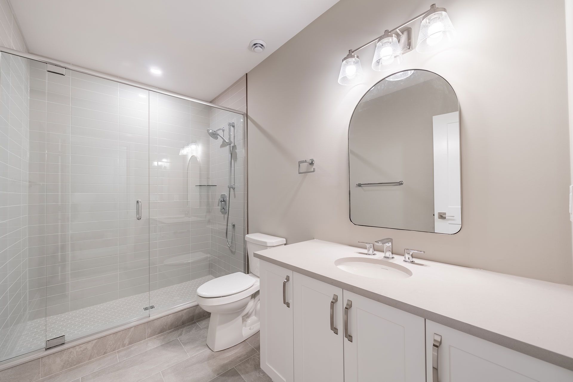 A bathroom with a toilet a sink and a mirror Fidelity Homes Signature build in Cramahe Township