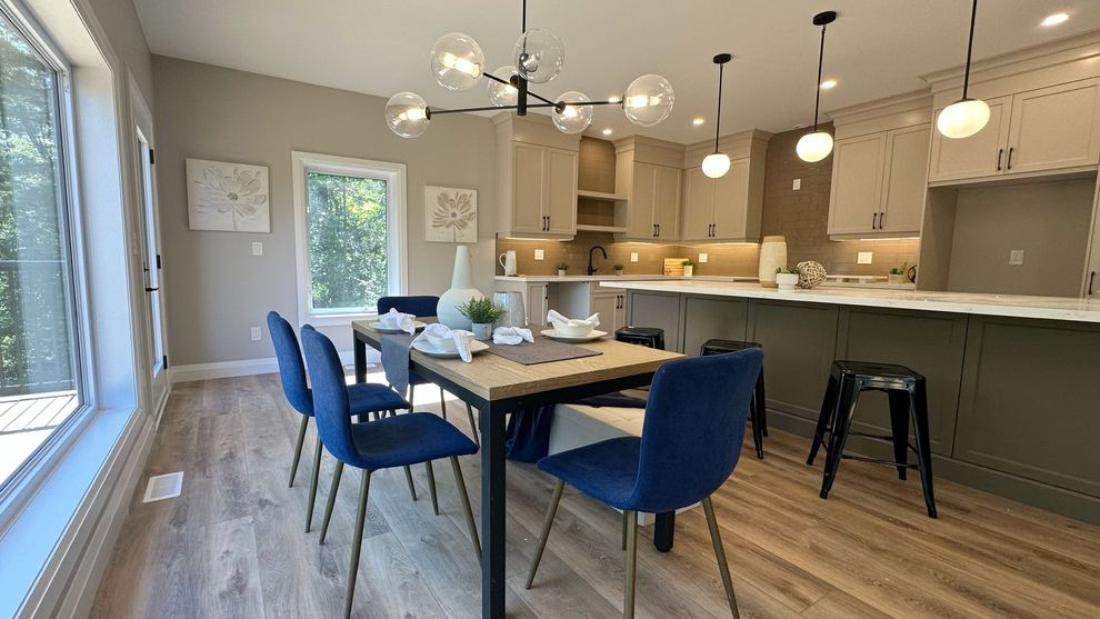 Modern open-plan kitchen and dining area with blue chairs, wood floors, and pendant lights