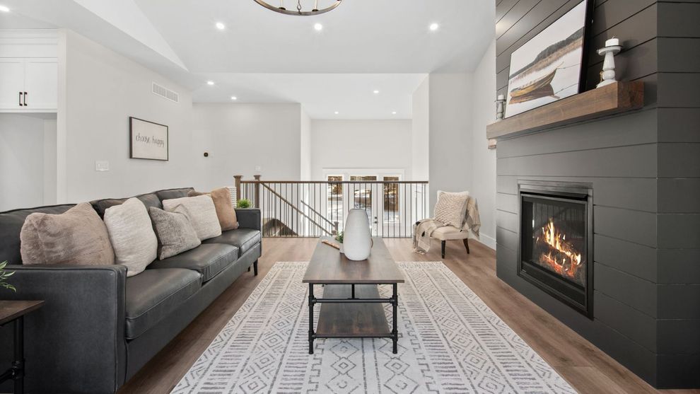Bright modern living room with gray sofa, fireplace, coffee table, and patterned rug