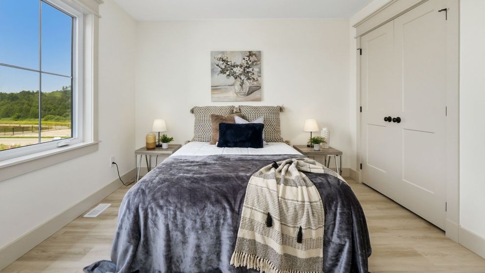 Bright minimalist bedroom with a bed, white walls, large window, and built-in closet doors