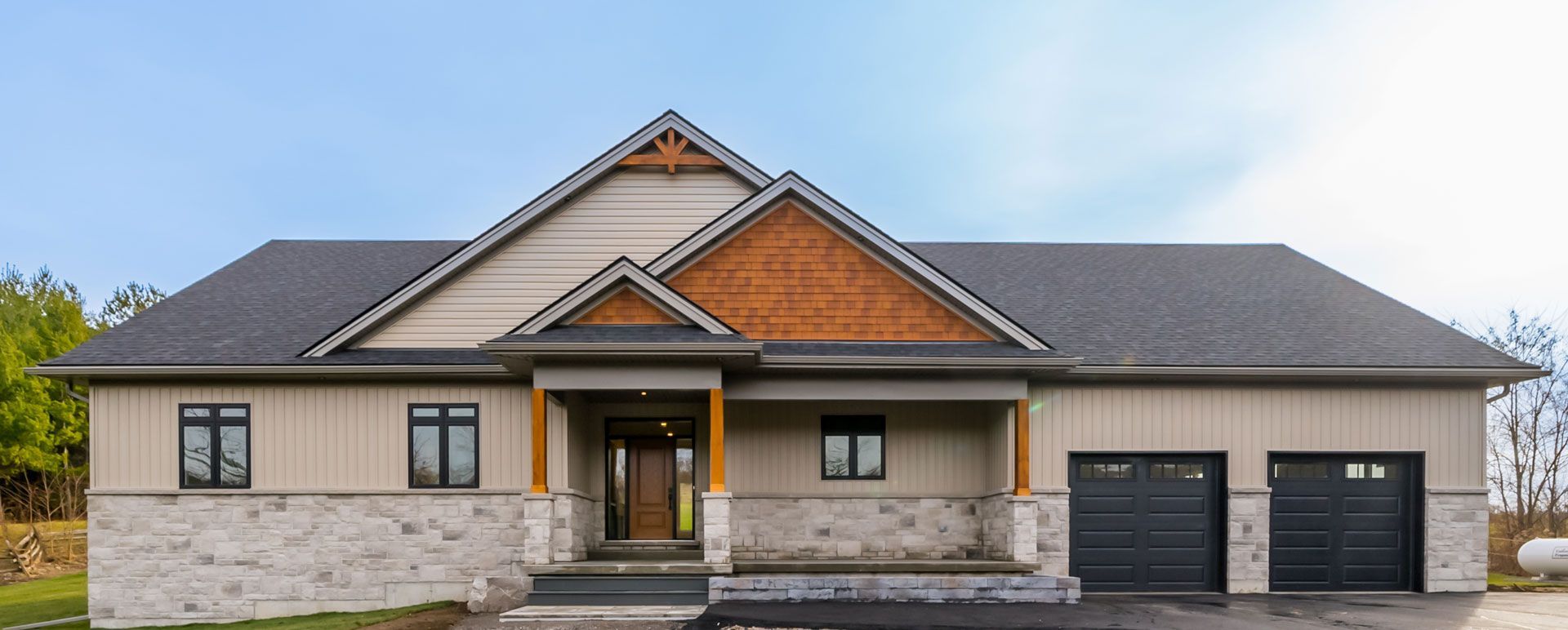A large Fidelity Homes signature build  with a grey roof and black garage doors