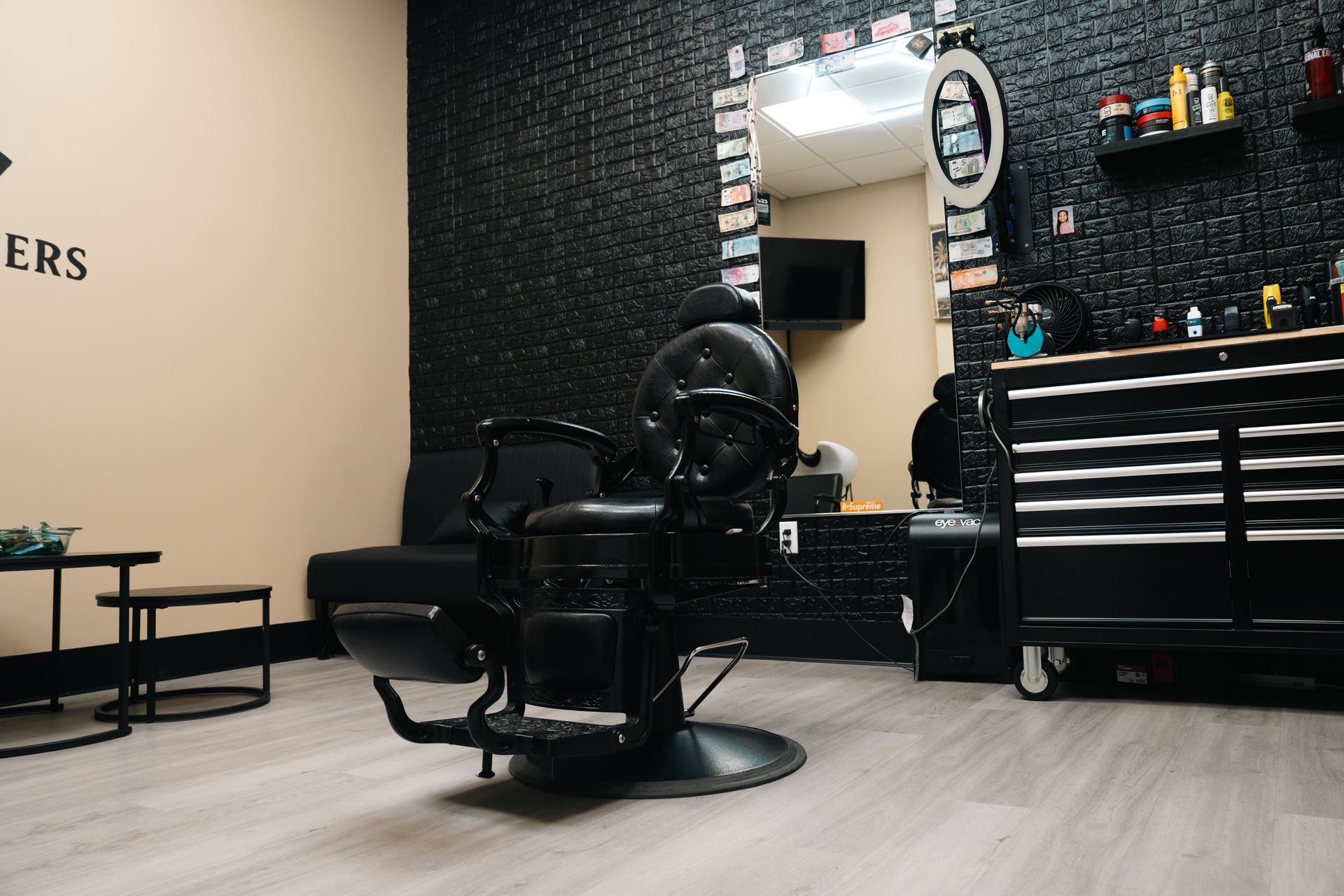 Modern barbershop interior with black barber chair, mirror, styling tools, and checkered wall.