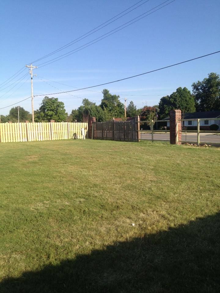A yard with a fence and a house in the background