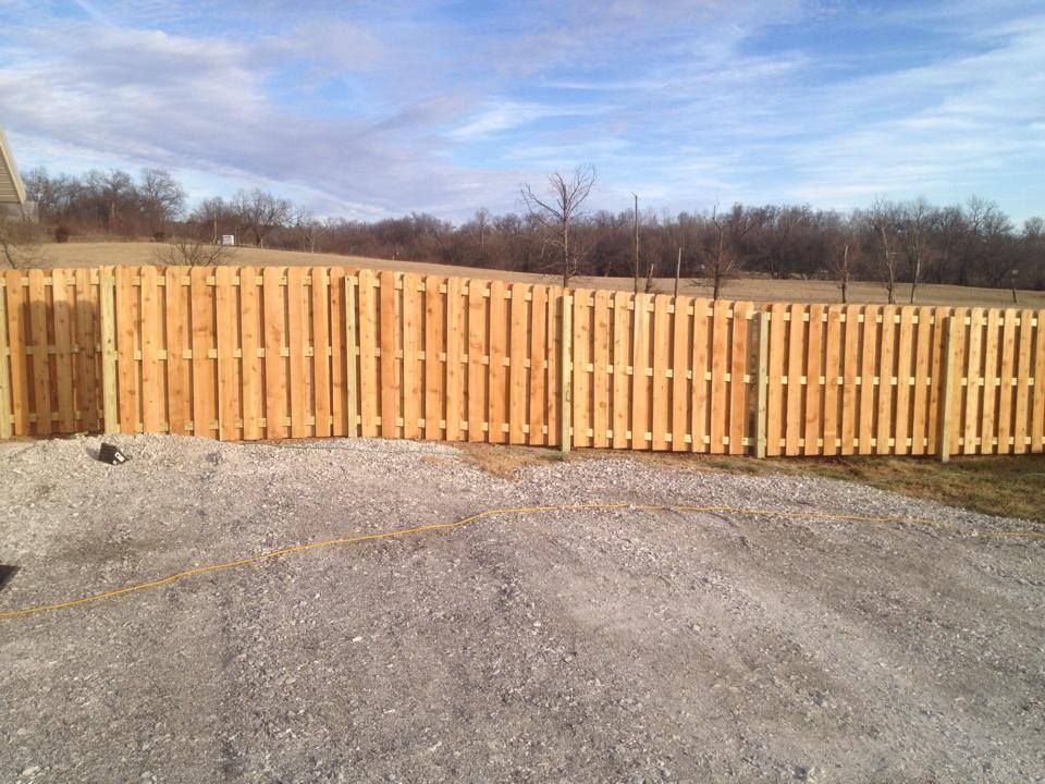A wooden fence is sitting on top of a gravel road.
