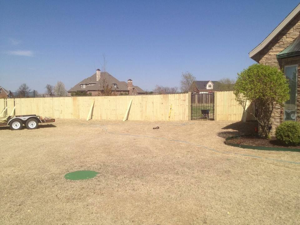 A wooden fence is being built in the backyard of a house.