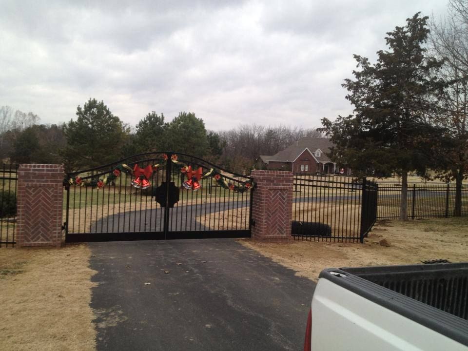 A white truck is parked in front of a wrought iron gate