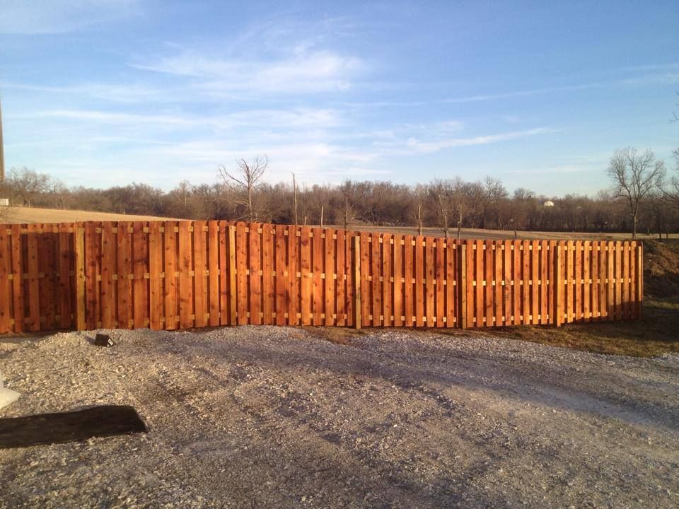 A wooden fence is sitting on top of a gravel road.
