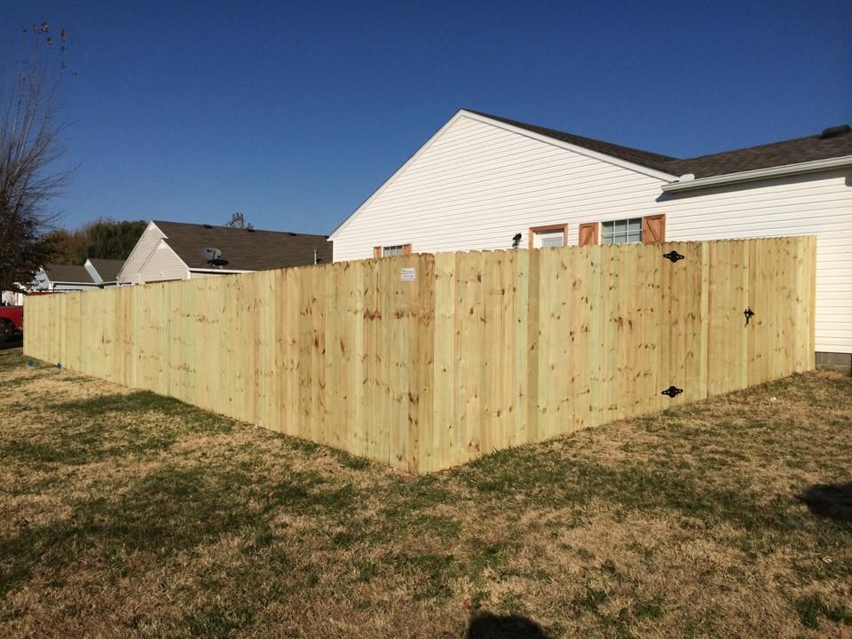A wooden fence is in the backyard of a house.