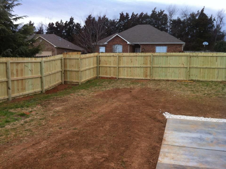 A wooden fence in a backyard with a house in the background