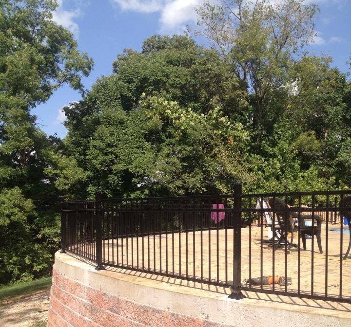 A fence surrounds a picnic area with trees in the background