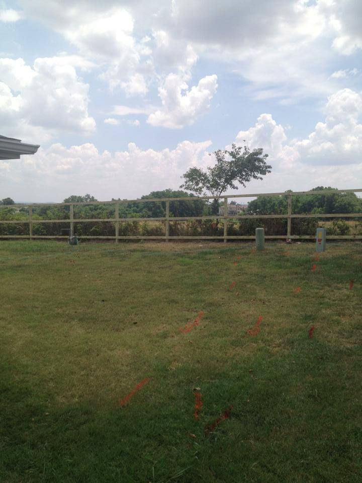 A grassy field with a fence and a tree in the background