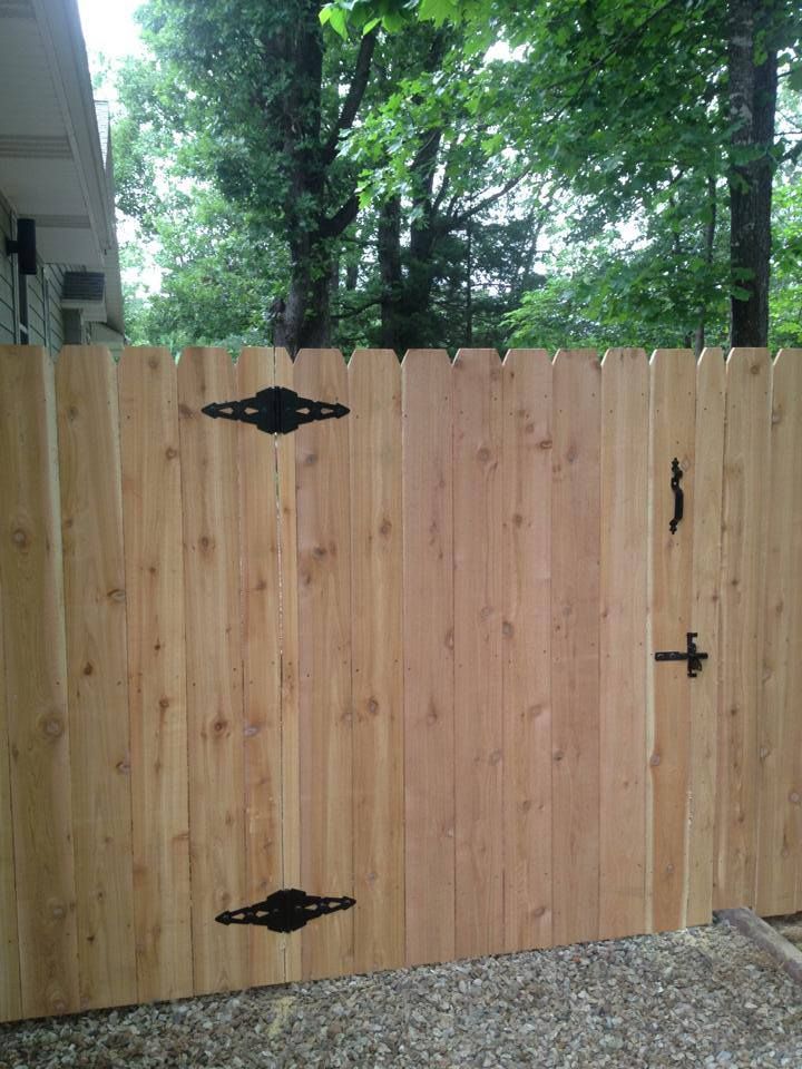 A wooden fence with a gate and trees in the background.