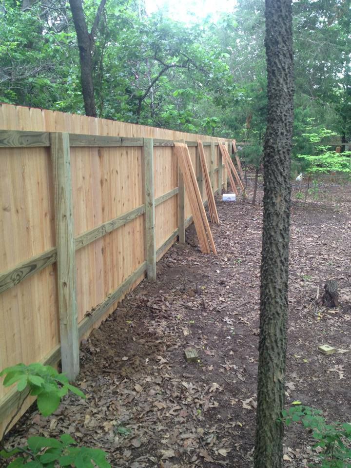 A wooden fence is being built in the middle of a forest.