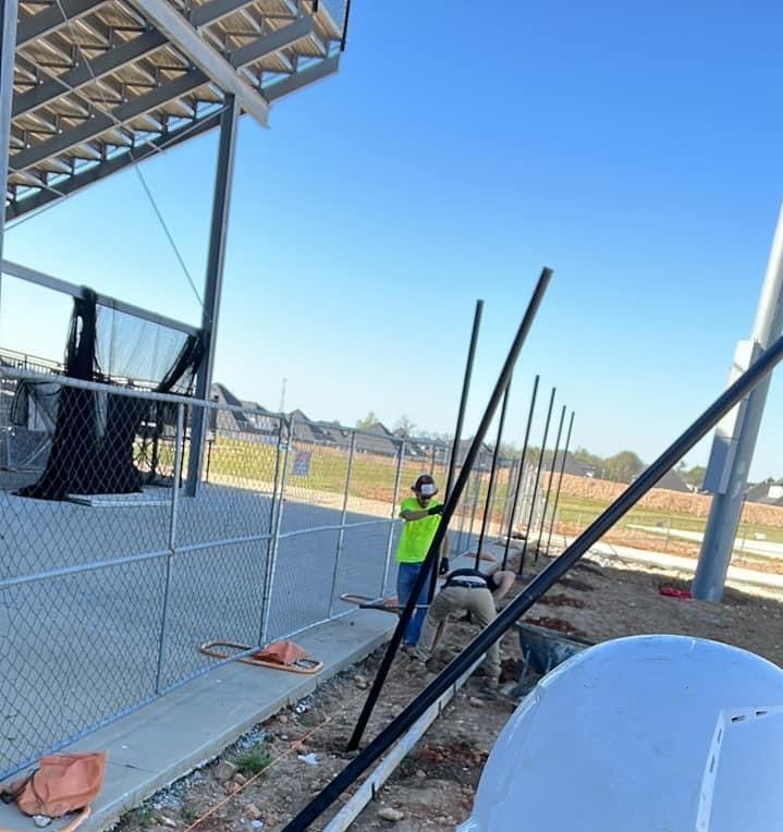 A man in a yellow vest is working on a fence