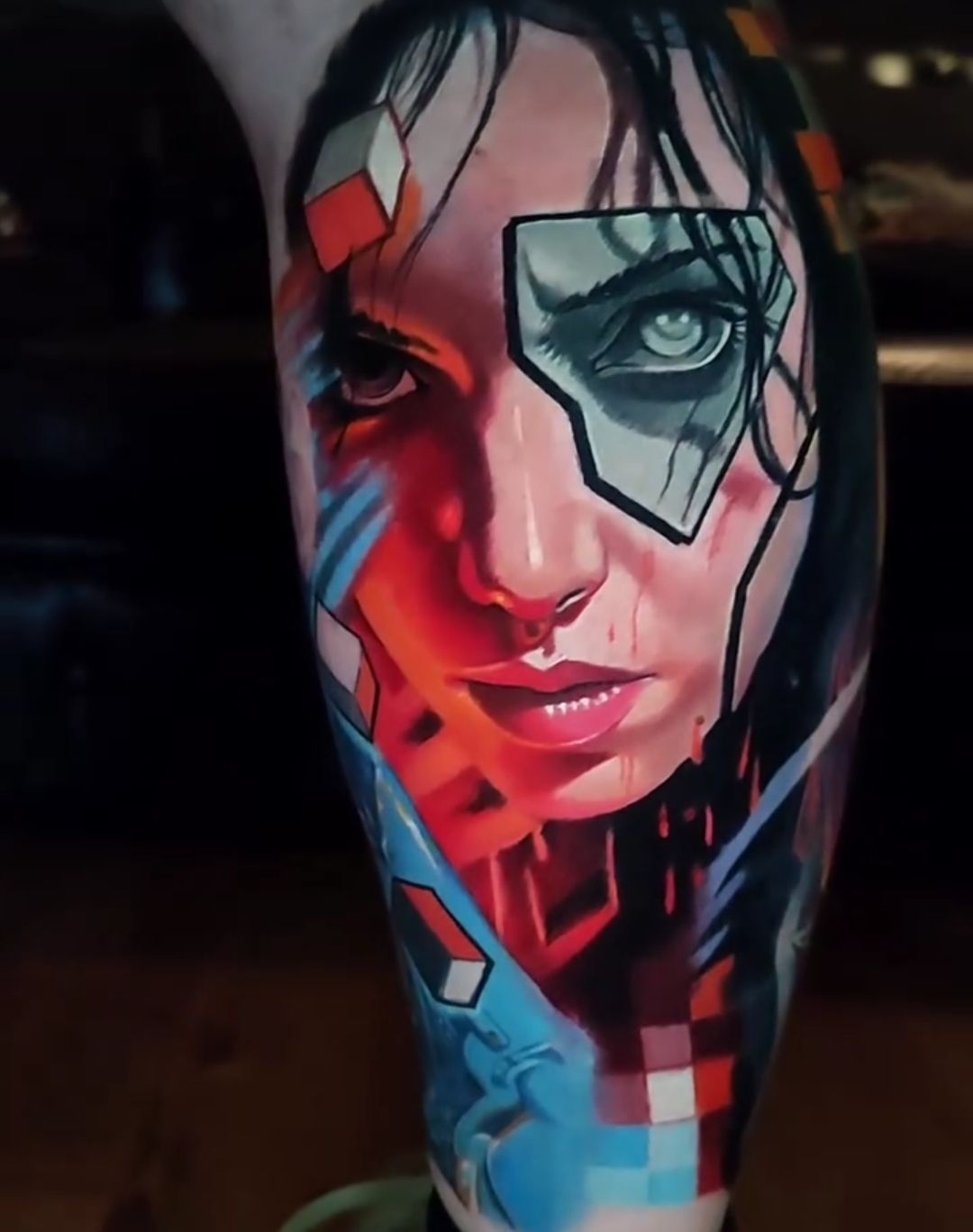 Realistic tattoo on leg of a woman with abstract geometric elements and vibrant colors.