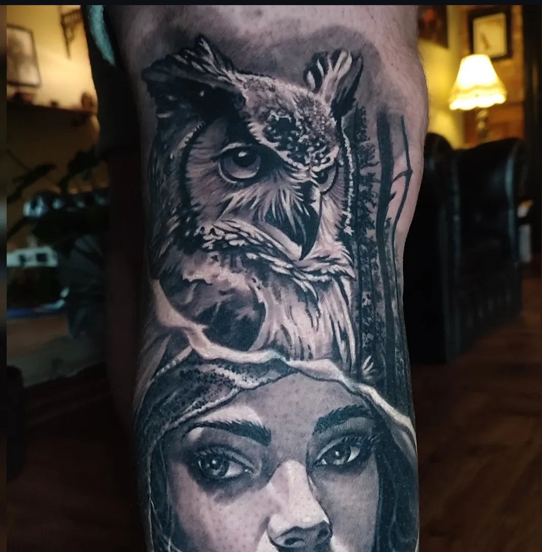 Tattoo of an owl above a woman's face, black and white.