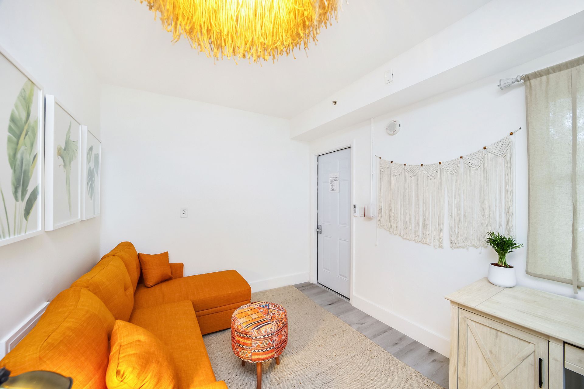 Cozy living room with orange sectional sofa, white walls, and decorative accents.