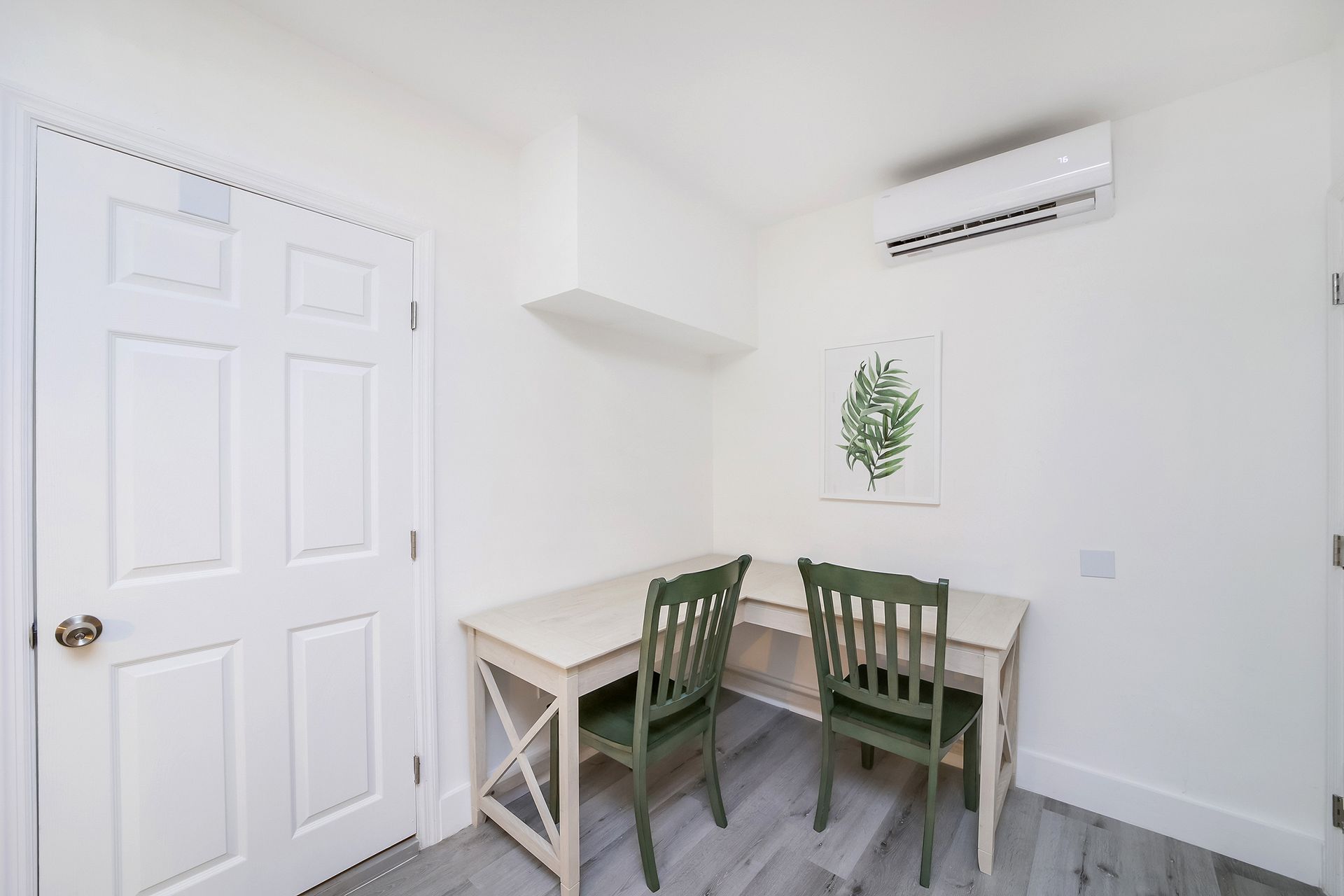 Desk nook with two green chairs, white walls, and a door.