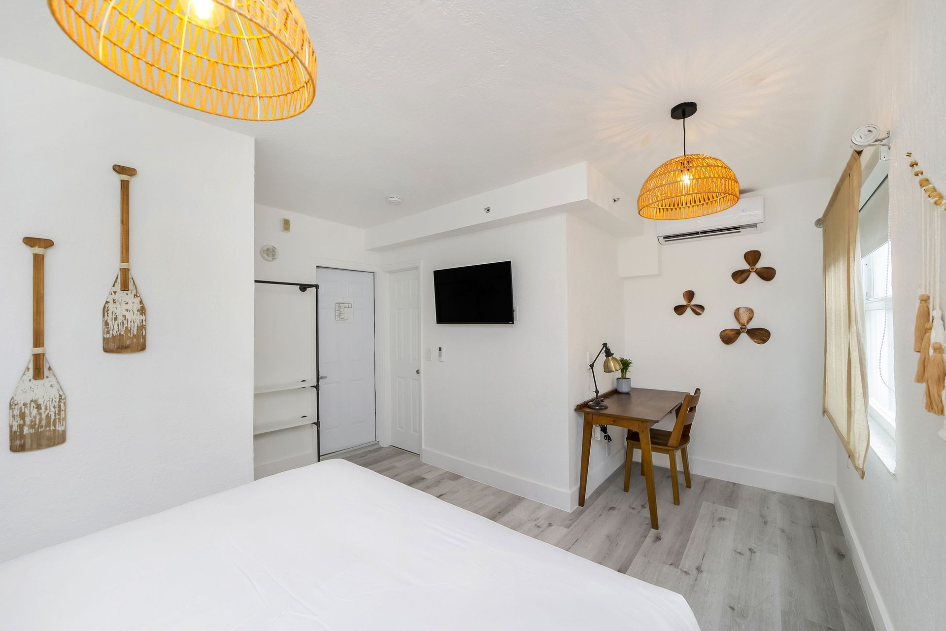 A bright white hotel room with nautical decor, including oars and wicker lamps.